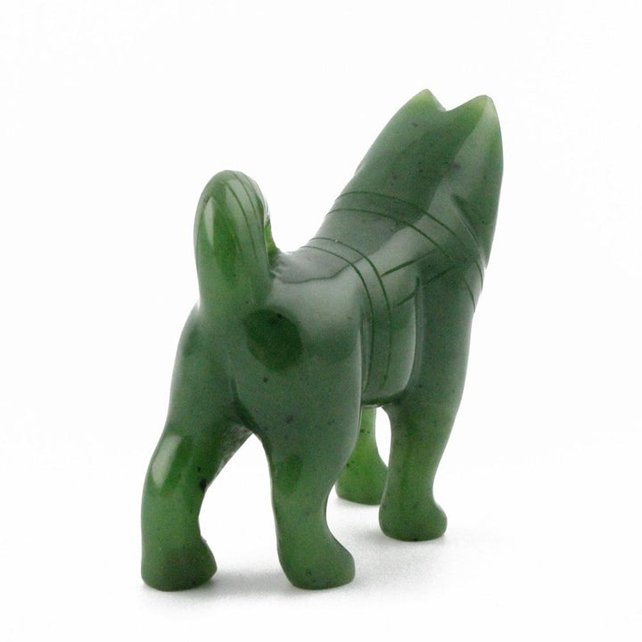 Rear-facing view of green stone husky figurine with curved tail.