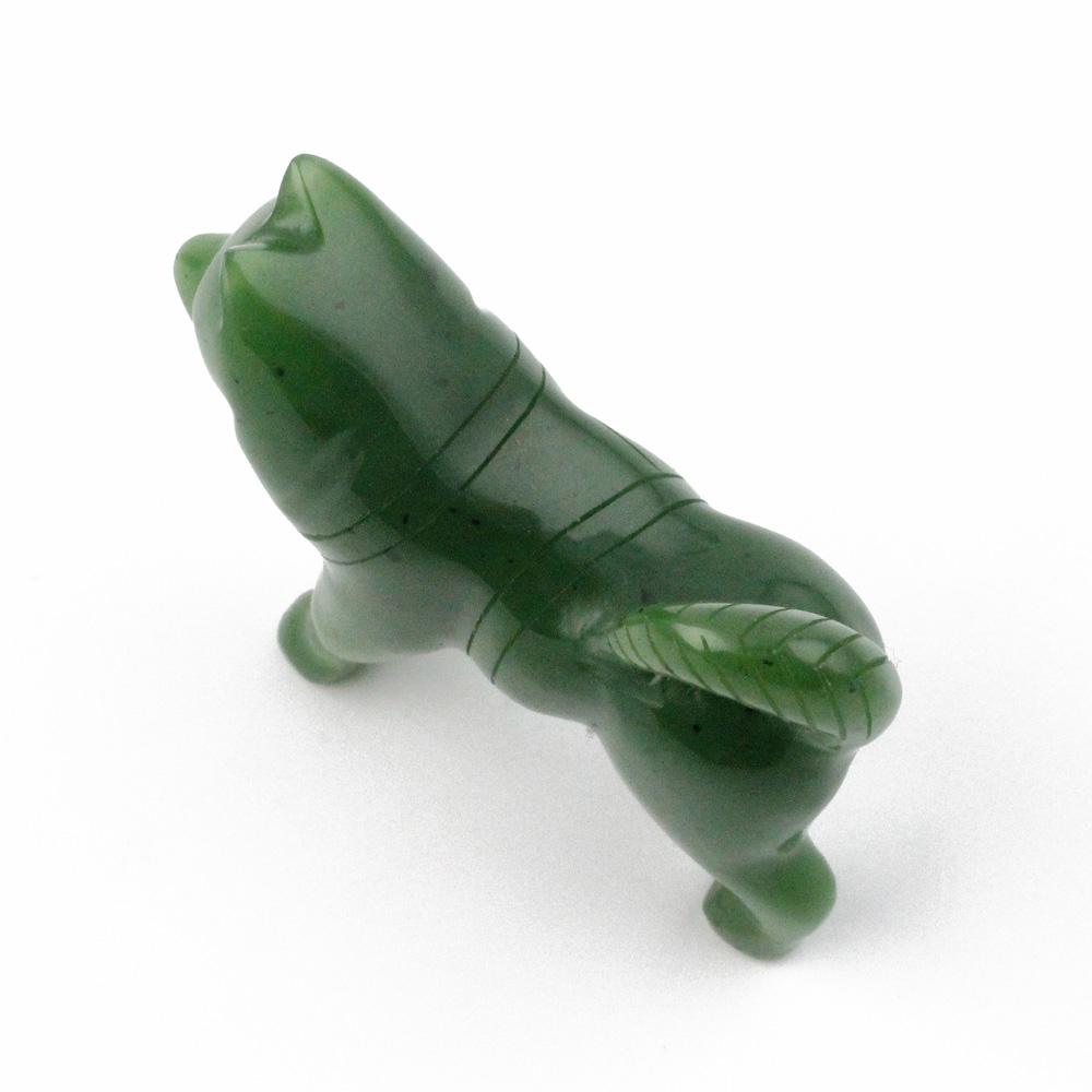 Top-angle view of green stone husky figurine with carved lines along its body.