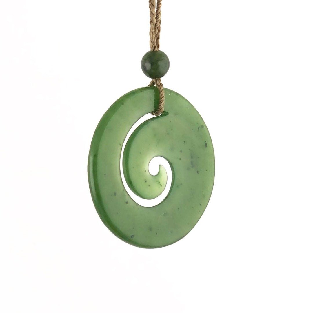 Green spiral koru pendant hanging from a natural braided cord
