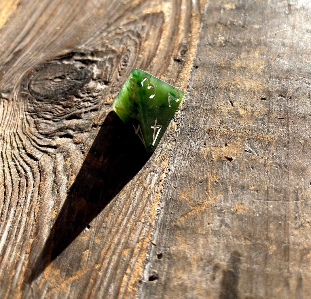 Green jade D4 die resting on a weathered wooden surface.