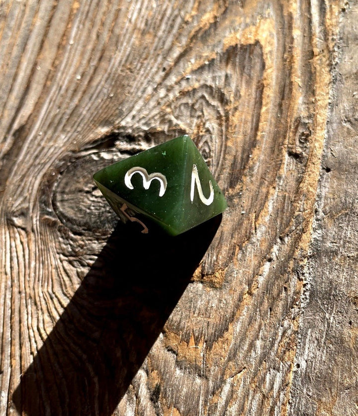 Green jade D8 die with white numerals on a weathered wooden surface
