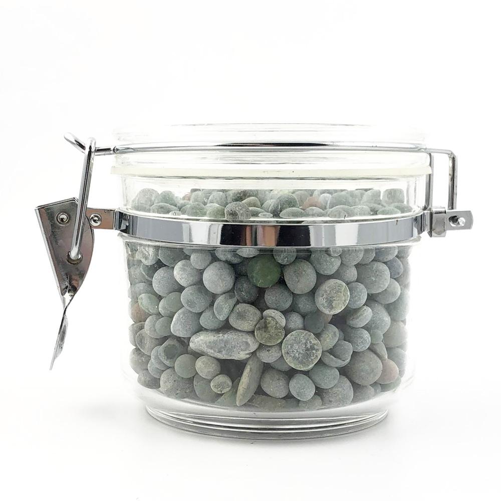 Side view of a clamp lid glass jar filled with green gray aquarium beads.