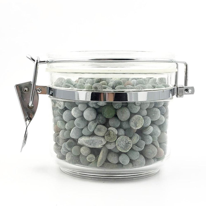 Side view of a clamp lid glass jar filled with green gray aquarium beads.