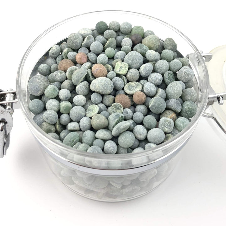 Green gray round aquarium beads in a clear glass jar.
