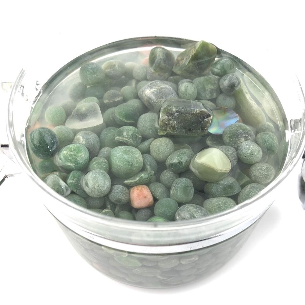 Clear glass jar filled with green aquarium beads with the lid open to the side