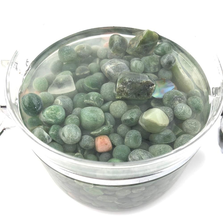 Clear glass jar filled with green aquarium beads with the lid open to the side