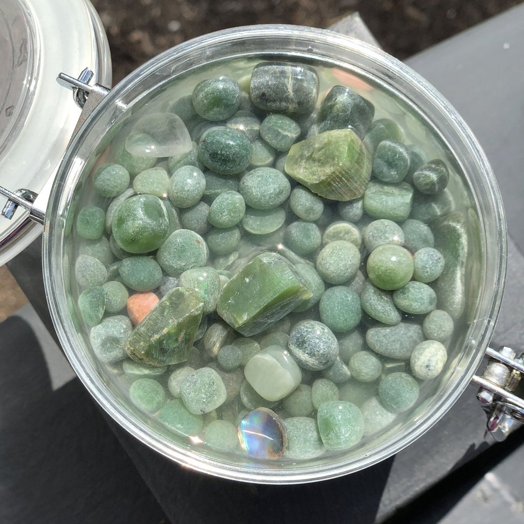 Round glass jar filled with green aquarium beads and tumbled stones