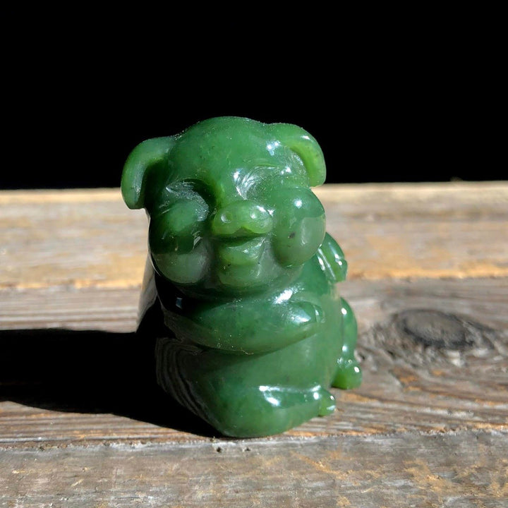 Green jade Jolly Jade pig figurine with glossy finish on a wooden surface