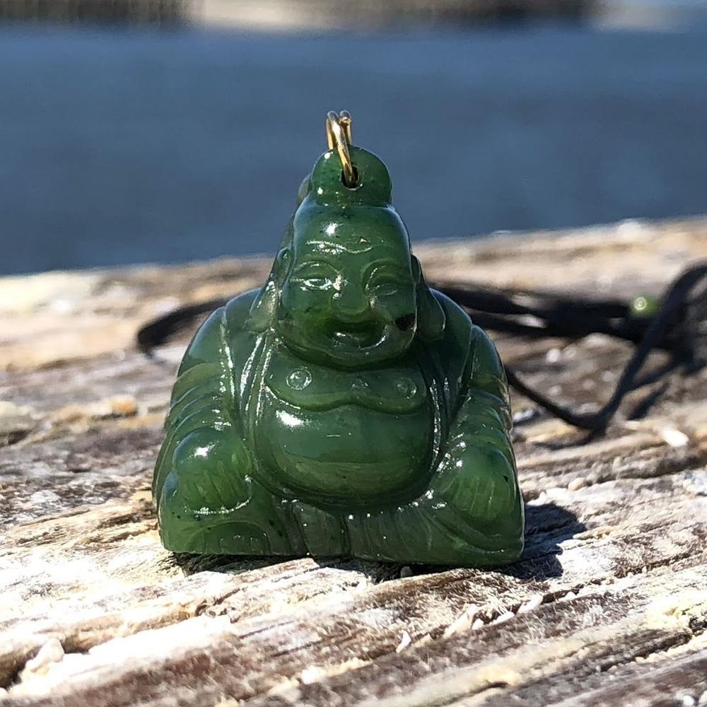 Green Happy Jade Buddha on top of wood with a blurred ocean background