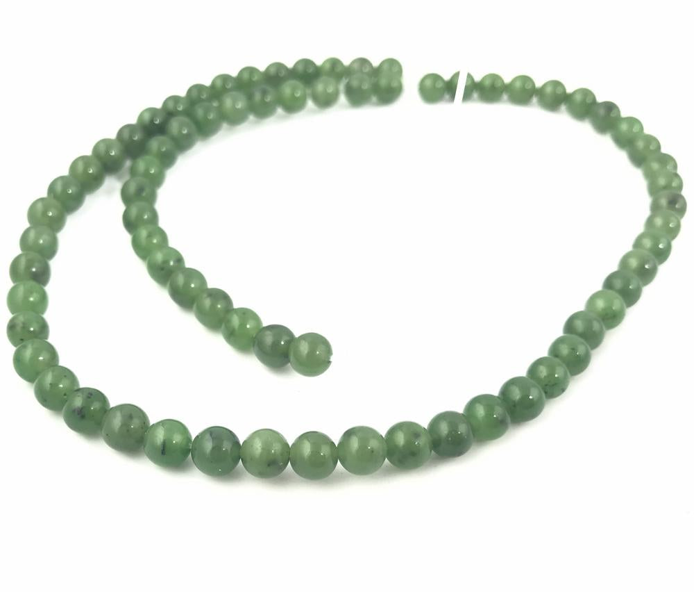 Green 6mm beads laid in a curved strand on white background