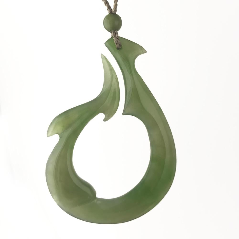Polar Jade pendant with an abstract teardrop shape in pale green, hanging from a braided cord