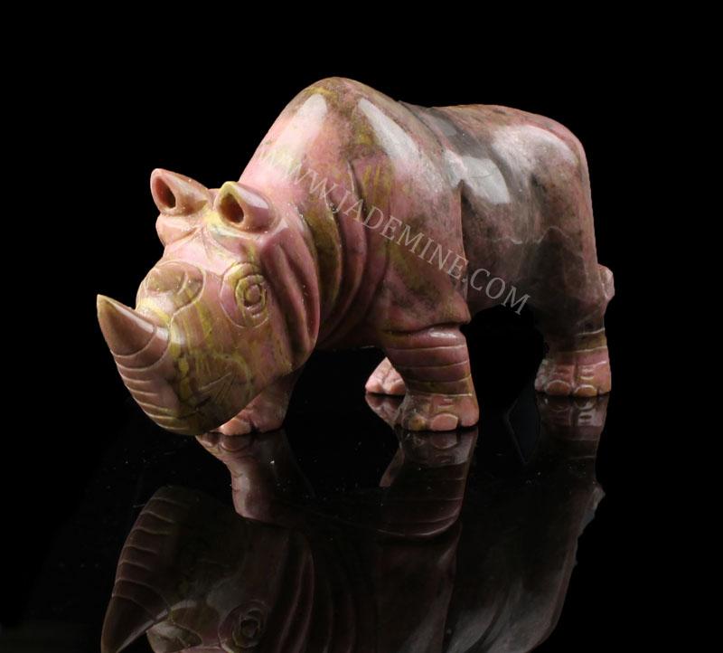 Pink rhodonite rhinoceros sculpture with gold streaks on a black background