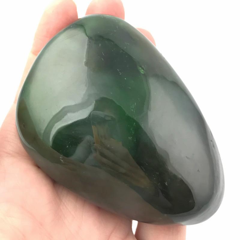 Glossy dark green jade teardrop held in a hand