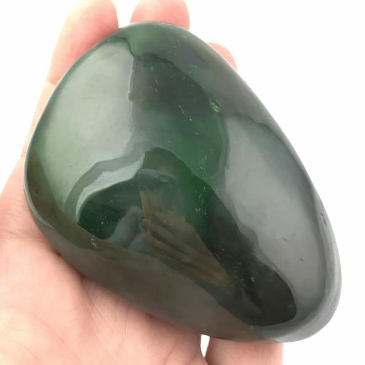 Glossy dark green jade teardrop held in a hand