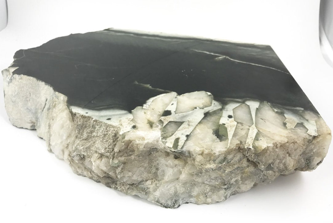 Olive Wyoming slab with a dark surface and white quartz crystal inclusions along the edge.