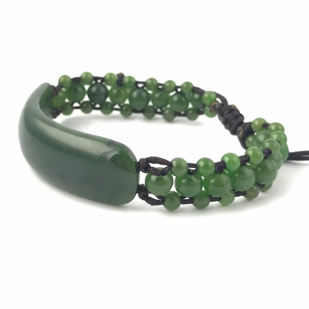 Green jade bracelet with a curved central bead and two strands of green beads on a black cord