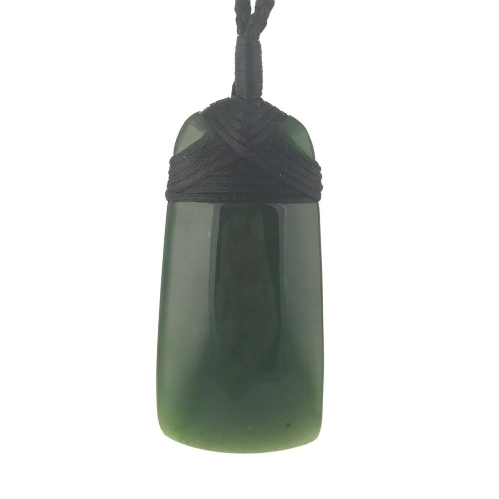 Green jade pendant wrapped in black cord with a woven top knot.