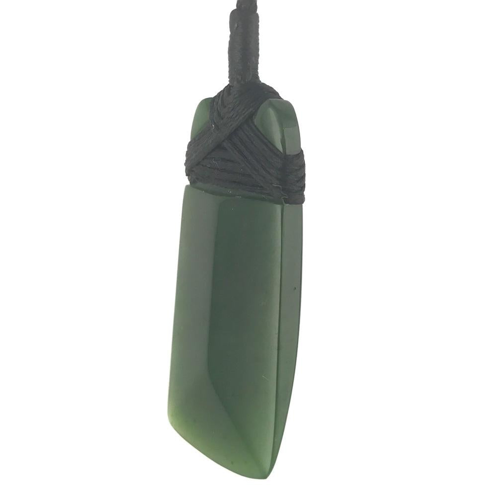 Green rectangular jade pendant bound with black cord and a loop at the top.