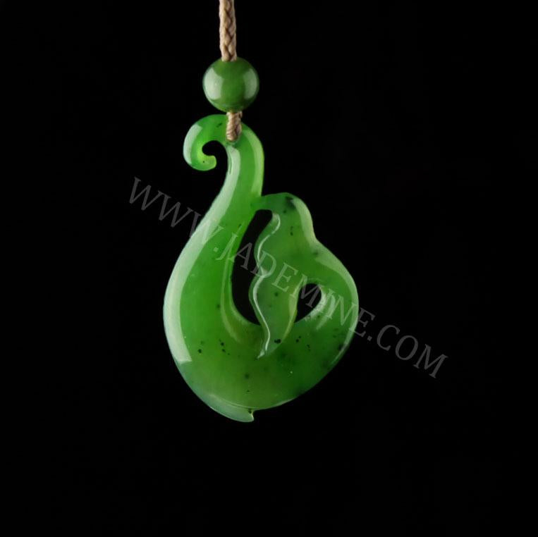 Close up of green jade pendant with flowing curved swirl on a beige cord against a black background