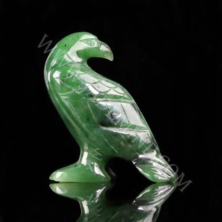 Green jade standing eagle sculpture on a black reflective surface.