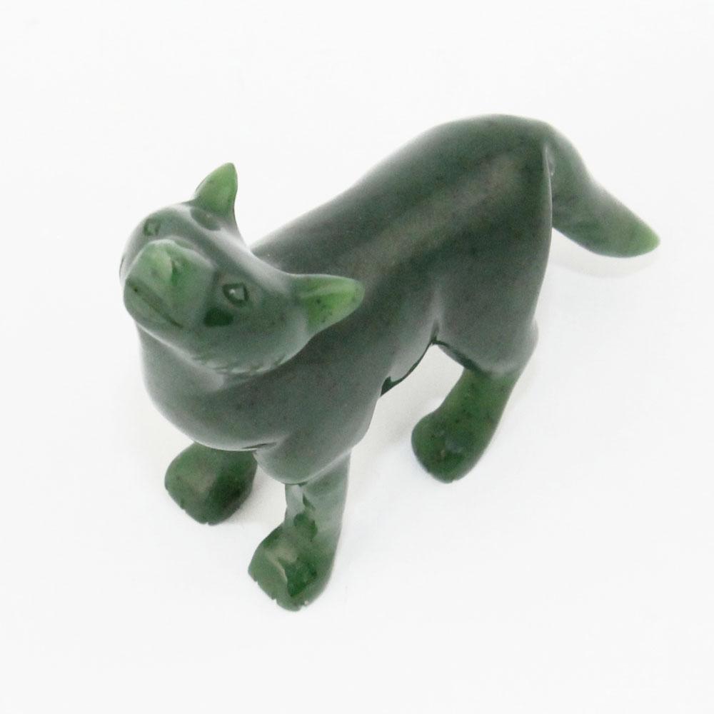 Green carved coyote figurine standing on four legs with head raised toward viewer.