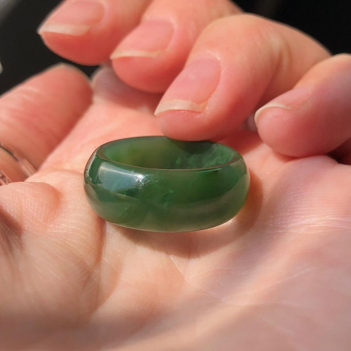 Wide jade ring in deep green being held in hand