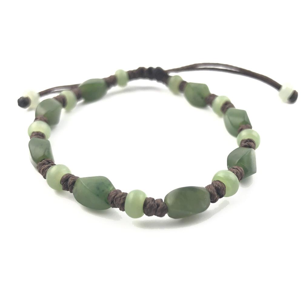 Green stone bracelet with alternating oval and round beads on brown cord displayed on white background.