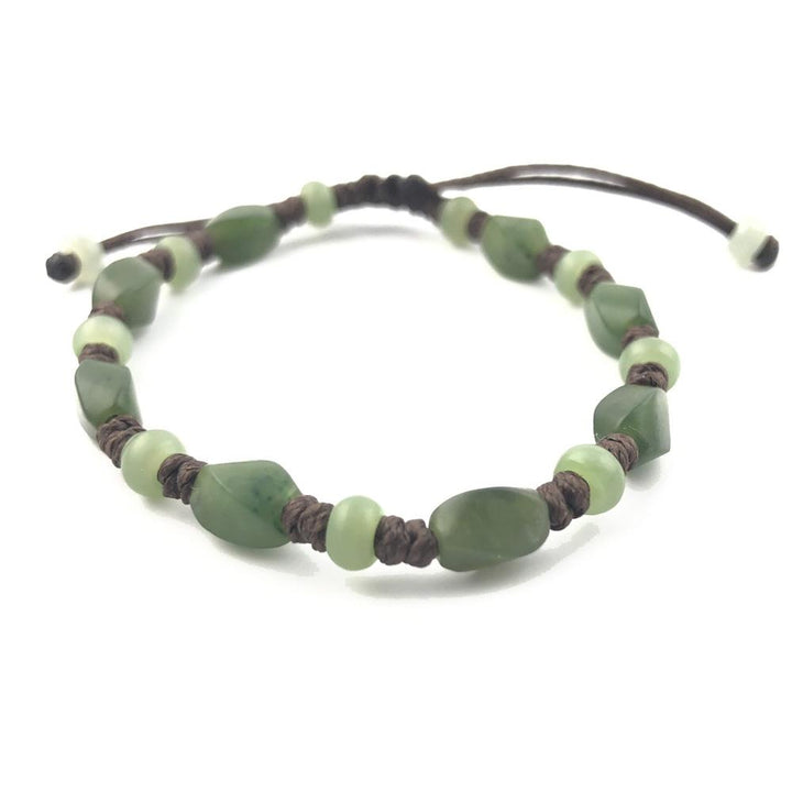 Green stone bracelet with alternating oval and round beads on brown cord displayed on white background.