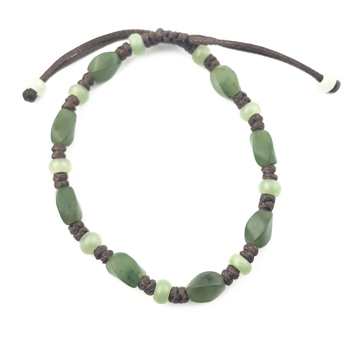 Bracelet with green stone chips and pale green beads on a dark braided cord.