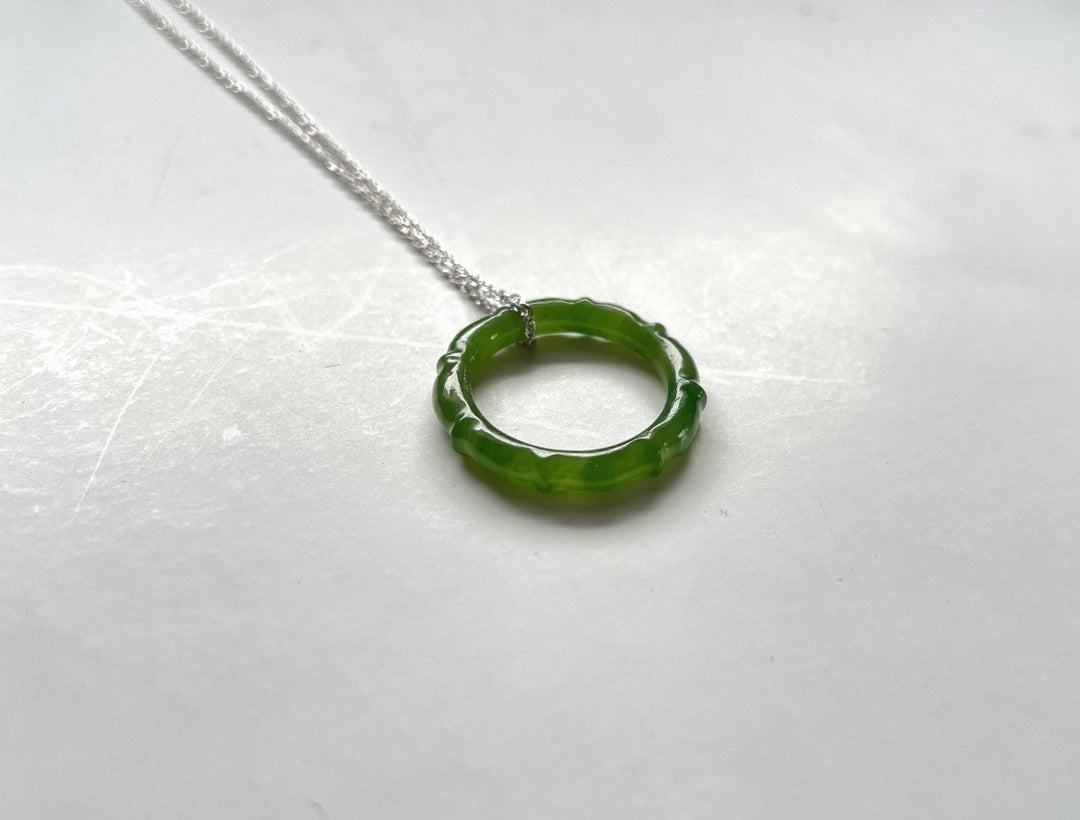 Circular green jade pendant with scalloped edge on a silver chain
