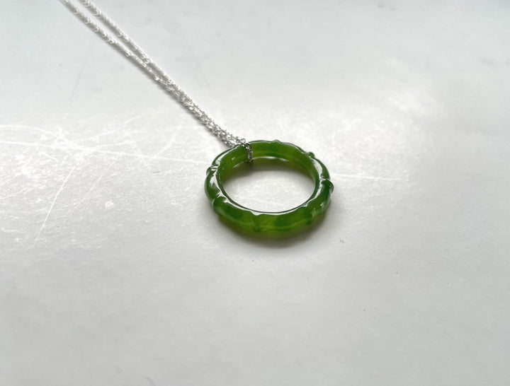 Circular green jade pendant with scalloped edge on a silver chain