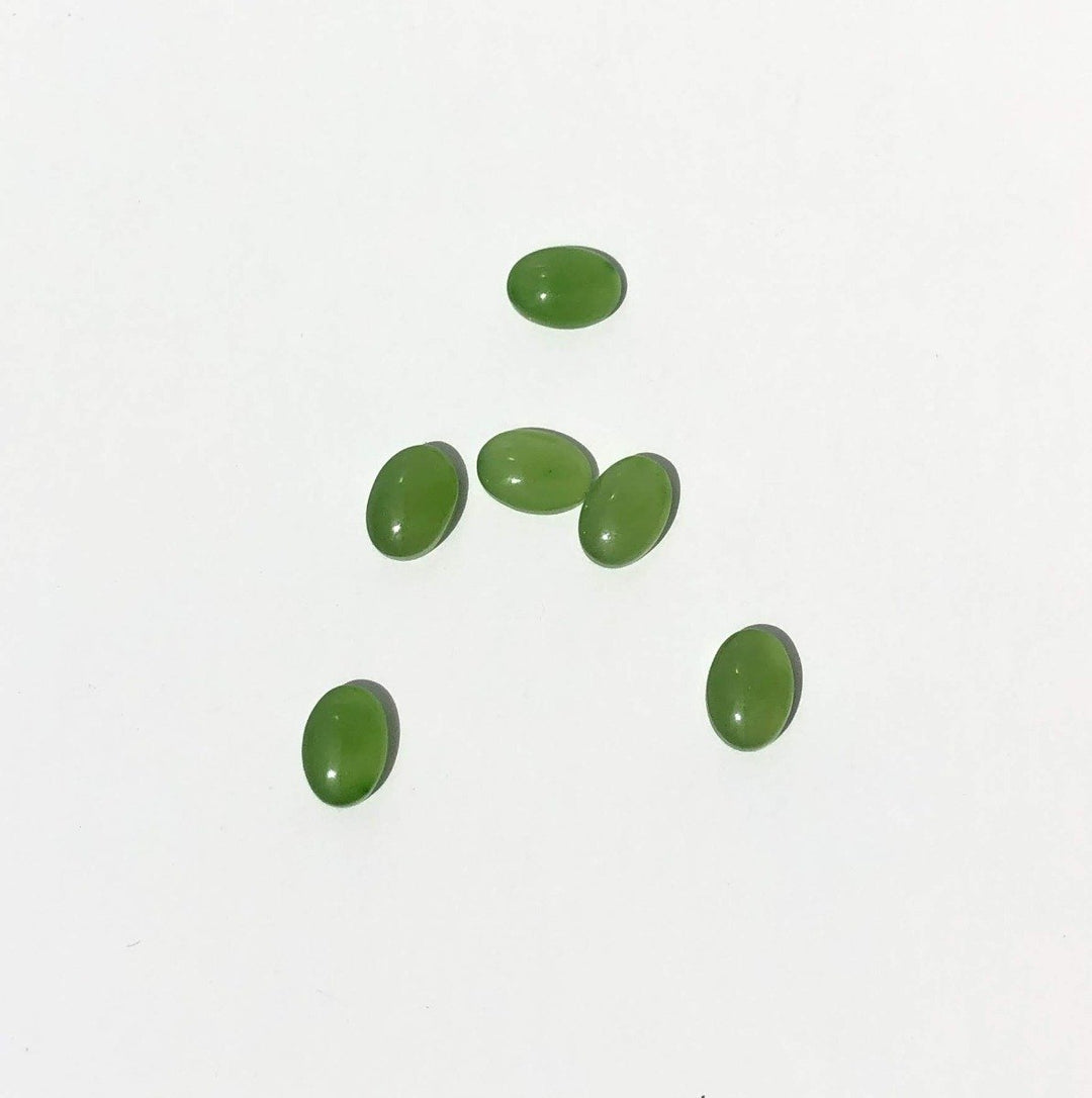 Green jade cabochons 5x7mm on a white background scattered