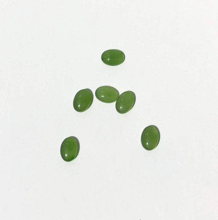 Green jade cabochons 5x7mm on a white background scattered