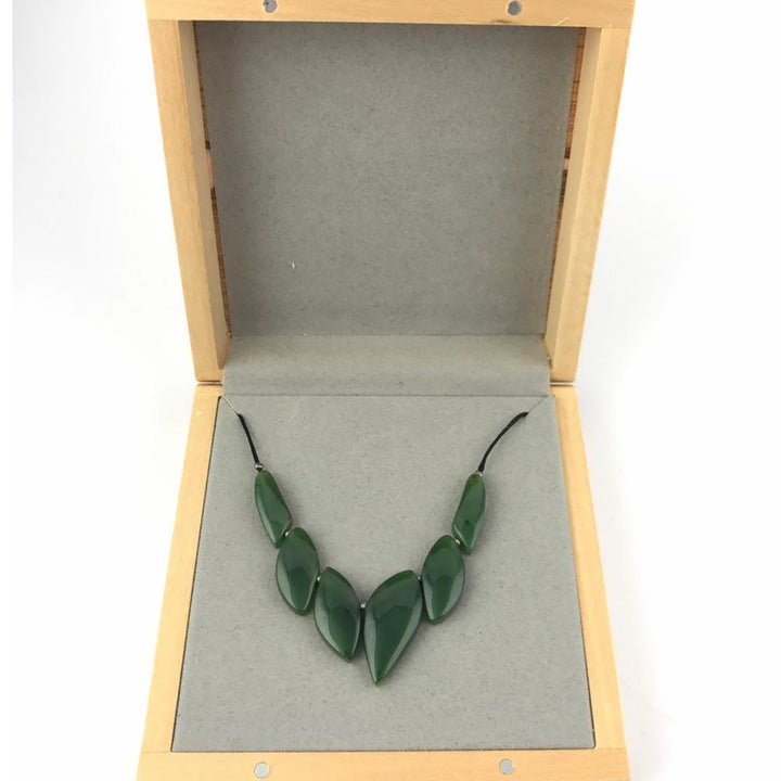 Jade bead necklace arranged in a V shape inside an open wooden display box