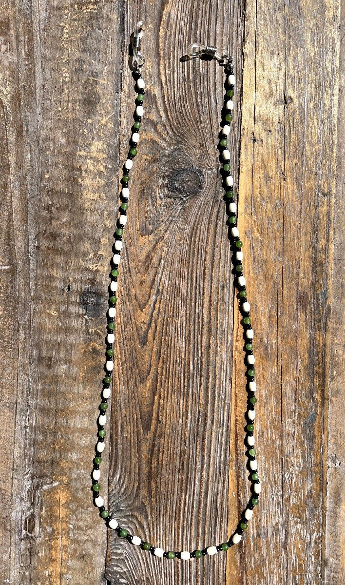 Jade and bone beaded mask or eyeglass holder with white bone beads and green jade beads on a rustic wooden surface.