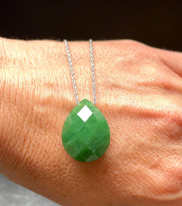 Faceted green teardrop pendant 17 by 22 mm on a silver chain worn on a hand