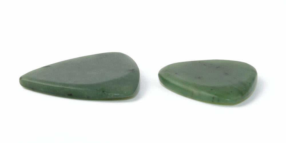 Two green jade guitar picks lying flat on a white surface.