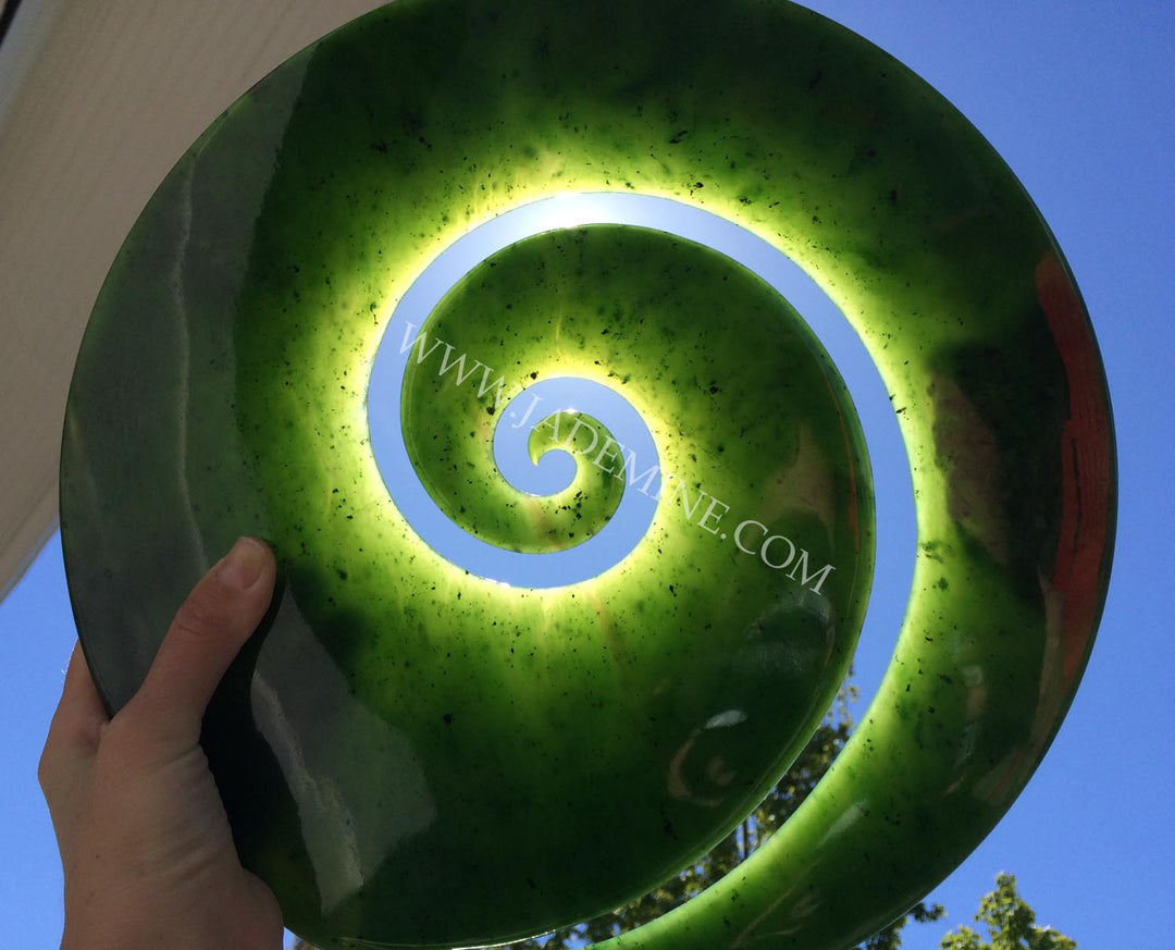 Green spiral sculpture held by a hand outdoors against a blue sky