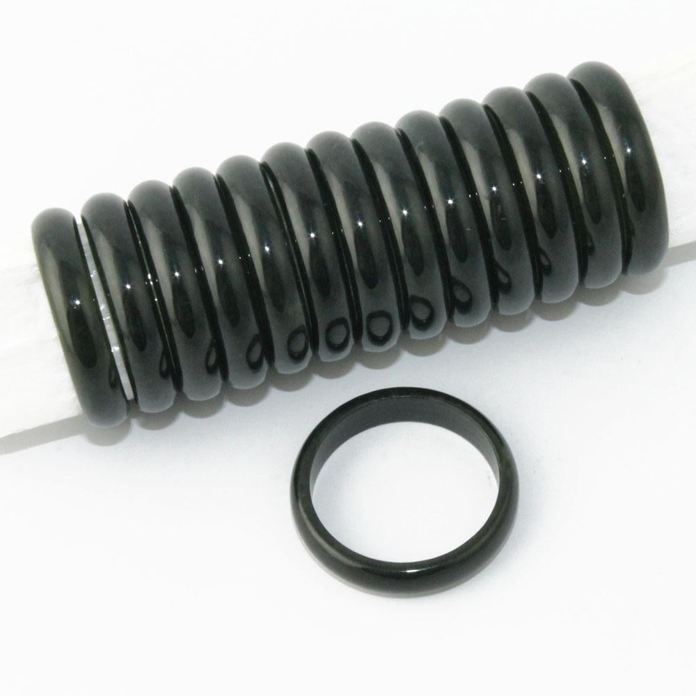 Row of glossy black jade ring spacers on a rod with a single ring placed nearby.