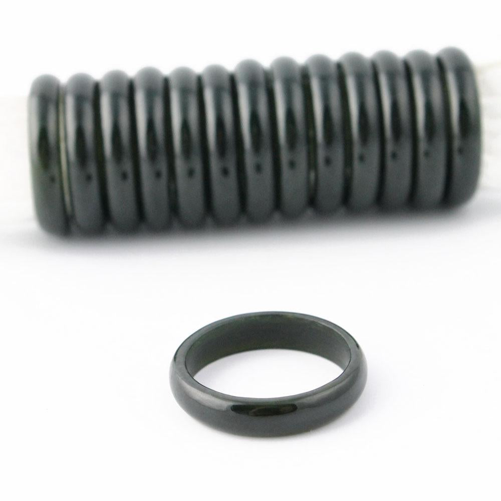Close-up of a glossy black jade narrow band ring with coiled rings in the background