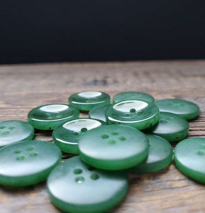 Group of green jade buttons scattered on a wooden surface