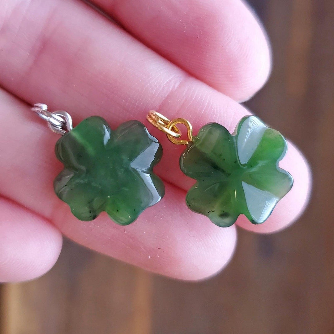 Two green four leaf clover jade charms with gold and silver bail attachments.